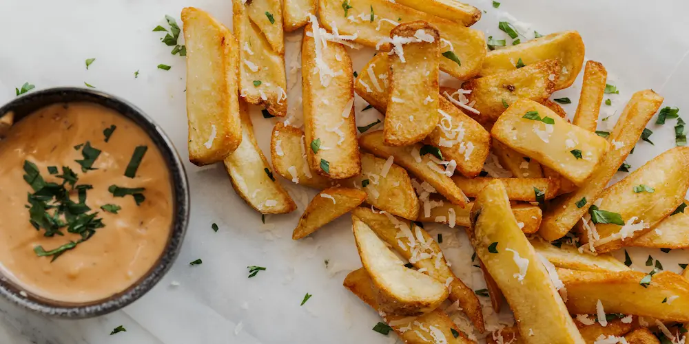 Potato wedges tossed in oil and seasoning spread in a single layer on a baking sheet