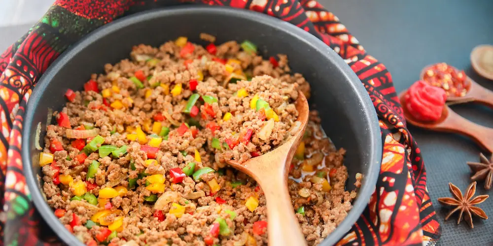 Loose ground beef browning and crumbling in a skillet on the stovetop