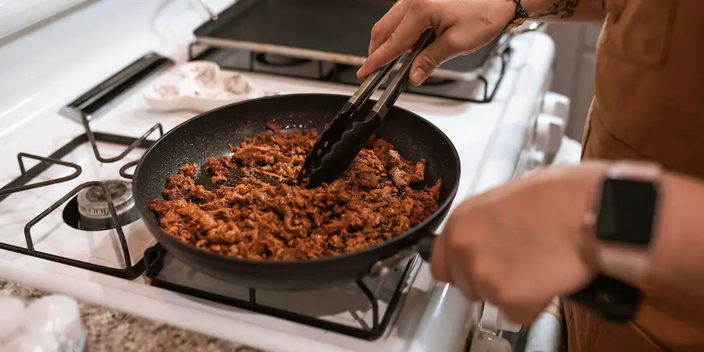 Overcrowded skillet of ground beef releasing liquid instead of browning